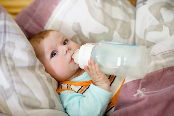 Bebê bebendo leite de garrafa. Bebê de 4 meses segurando o próprio frasco . — Fotografia de Stock