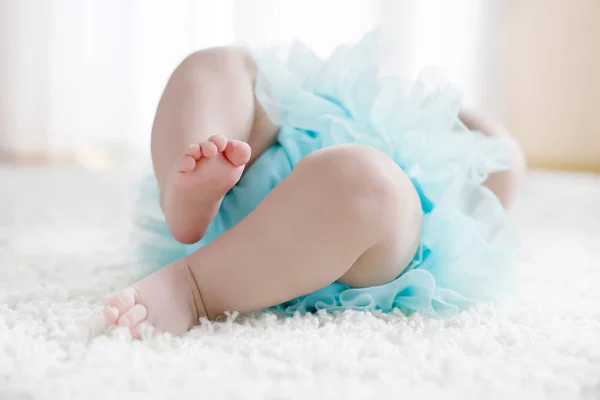Närbild av ben och fötter med baby girl på vit bakgrund bär turkos tutu kjol. — Stockfoto