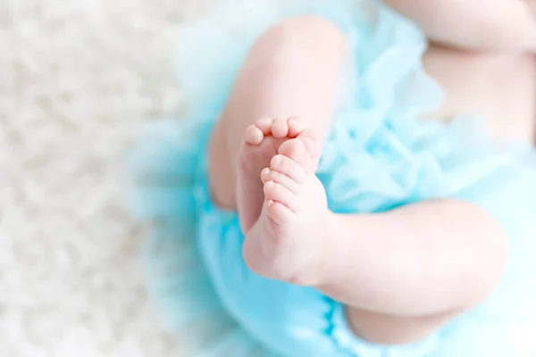 Close-up of legs and feet of baby girl on white background wearing turquoise tutu skirt. — Stock Photo, Image