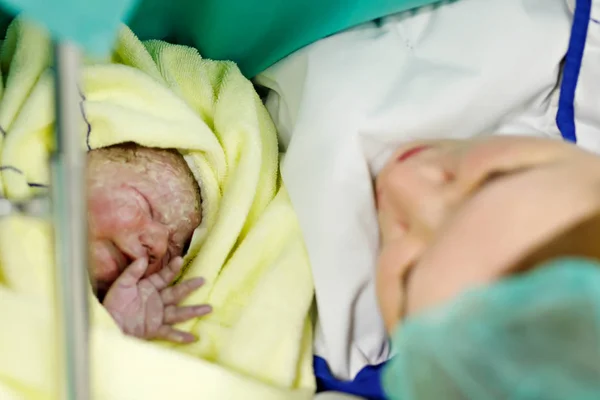 Bebé recién nacido envuelto en mantas después del nacimiento. Madre buscando por primera vez en la hija recién nacida — Foto de Stock