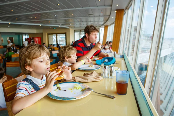 クルーズ船の 2 つの就学前の子供の男の子と父親カフェに座ってハンバーガーを食べる — ストック写真