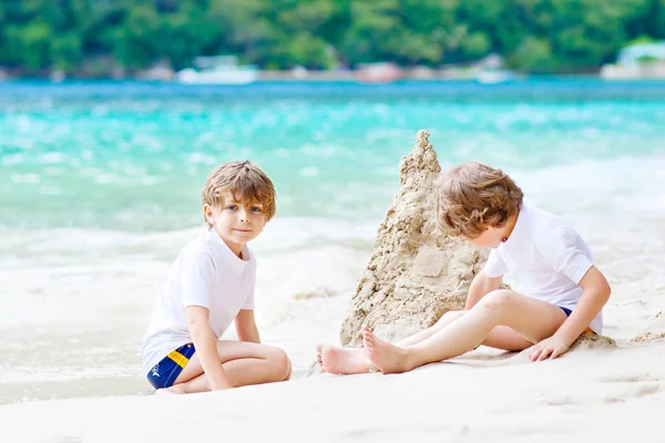 Twee jongen jongens bouwen van zandkasteel op tropisch strand — Stockfoto