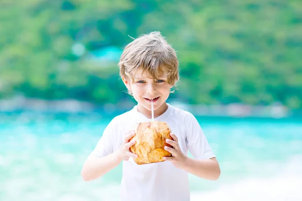 Little kid boy drinking coconut juice on tropical beach — Stock Photo, Image