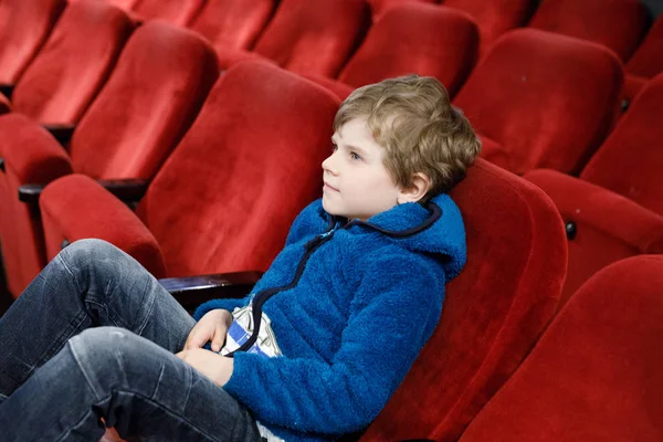 Mignon blond petit garçon manger pop-corn au cinéma avant que le film commence — Photo