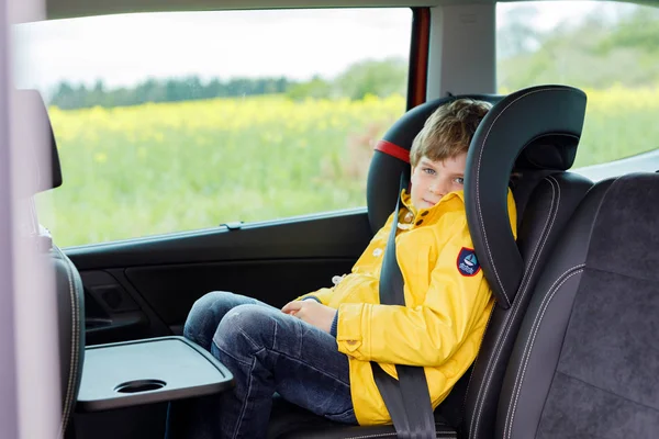 Adorable cute preschool kid boy sitting in car in yellow rain coat. — Stock Photo, Image