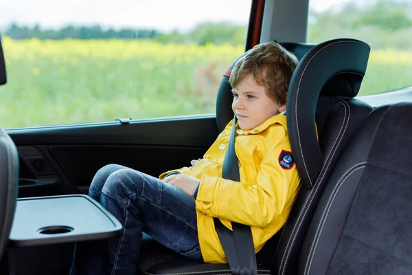 Adorable cute preschool kid boy sitting in car in yellow rain coat. — Stock Photo, Image