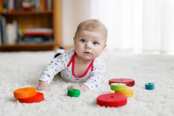 Schattige babymeisje spelen met kleurrijke houten rammelaar speelgoed — Stockfoto