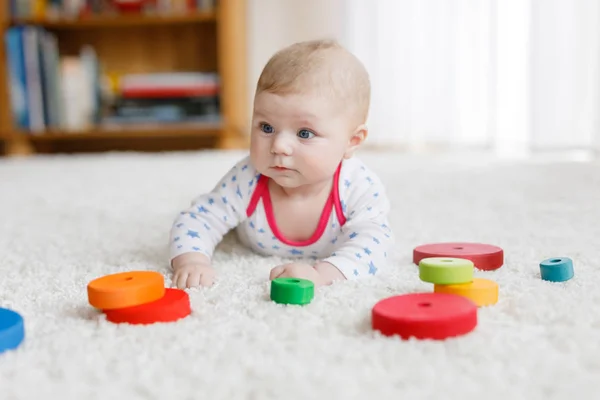 Schattige babymeisje spelen met kleurrijke houten rammelaar speelgoed — Stockfoto