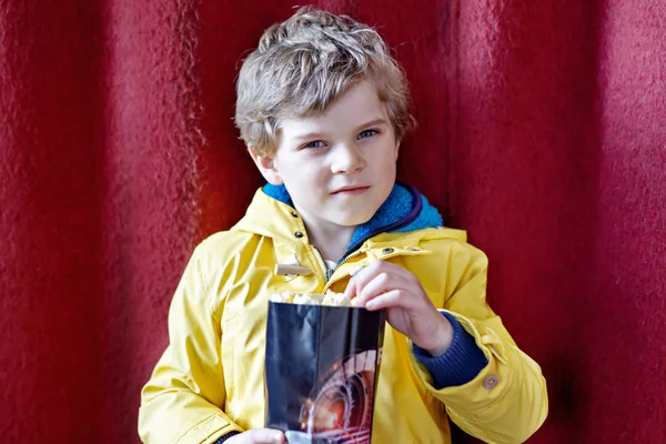 Cute blond little kid boy eating popcorn at the cinema before the movie starts — Stock Photo, Image