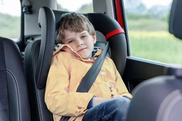 Ładny ładny przedszkolu dziecko chłopiec siedzi w samochodzie w Płaszcz przeciwdeszczowy żółty. — Zdjęcie stockowe