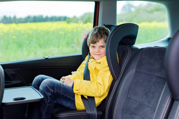 Adorable cute preschool kid boy sitting in car in yellow rain coat. — Stock Photo, Image