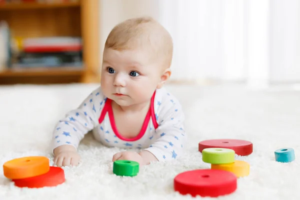 Schattige babymeisje spelen met kleurrijke houten rammelaar speelgoed — Stockfoto