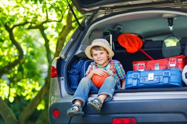 Sadece vaca için ayrılmadan önce araba bagajında oturan küçük çocuk çocuk