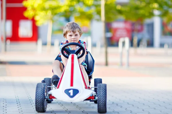 Маленький мальчик за рулем педали гоночного автомобиля летом — стоковое фото