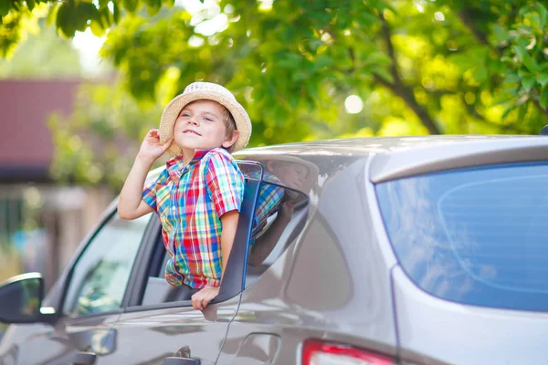 Menino pequeno sentado no carro pouco antes de sair para férias — Fotografia de Stock