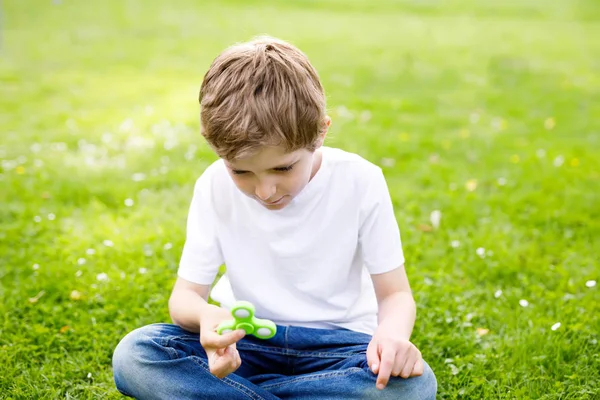 School kind spelen met Tri Fidget Hand Spinner outdoors — Stockfoto