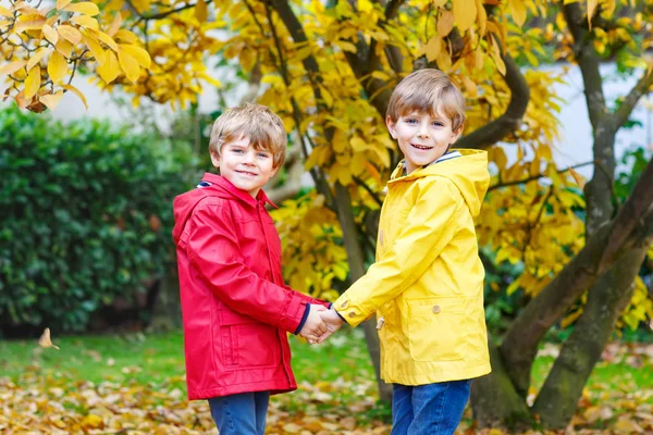 Due piccoli migliori amici e bambini ragazzi autunno parco in vestiti colorati . — Foto Stock