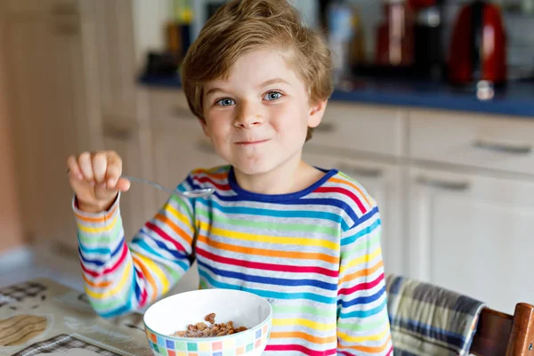 Glad liten blond kid pojke äter spannmål för frukost eller lunch. Hälsosam kost för barn. — Stockfoto