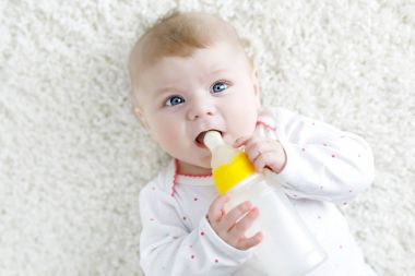 Sevimli, sevimli, doğma büyüme bebek, elinde süt şişesi var ve mama sütü içiyor.