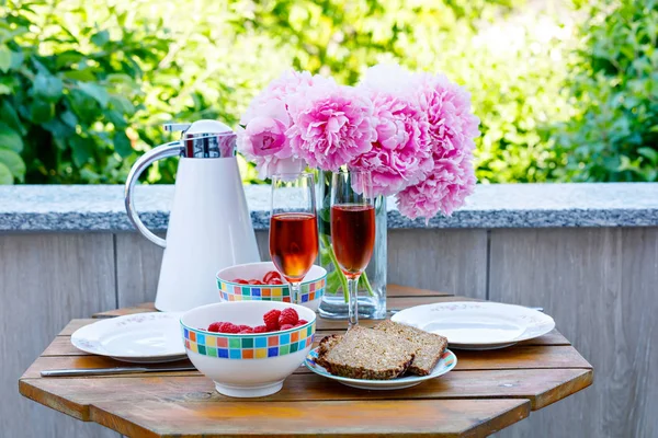 Breakfast table with bread, frest vegetables and berries, coffee and champagne served on balkony or hotel on summer morning — Stock Photo, Image