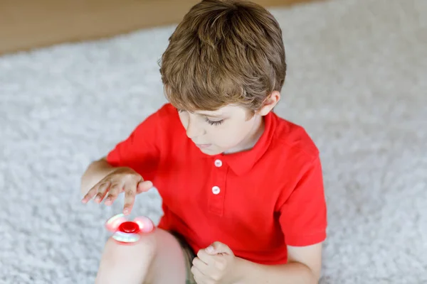 Niño de la escuela jugando con Tri Fidget Hand Spinner en interiores — Foto de Stock