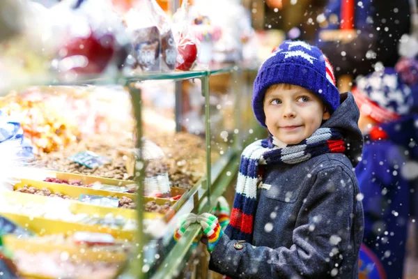 Little kid boy with gingerbread and sweets stand on Christmas market — Stock Photo, Image