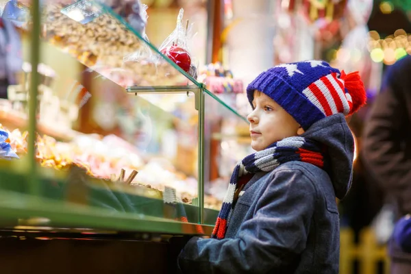 Dítě chlapec s perníkem a sladkosti stojí na vánoční trh — Stock fotografie