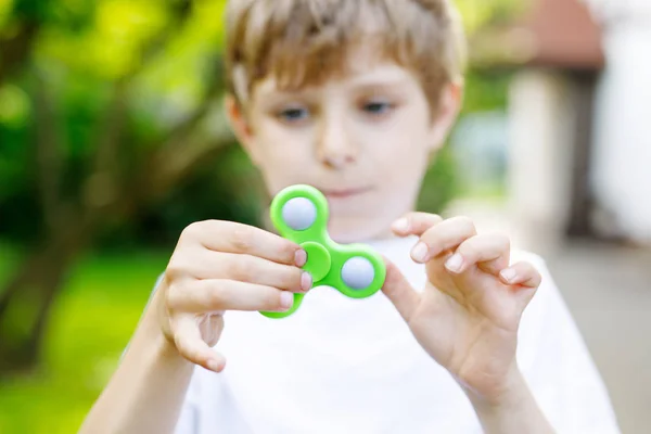 Escuela niño jugando con Tri Fidget Hand Spinner al aire libre — Foto de Stock