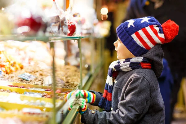 ジンジャーブレッドとお菓子と子供男の子がクリスマス マーケットの上に立つ — ストック写真