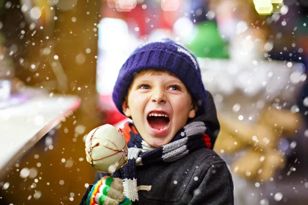 Маленький мальчик ест сладкие яблочные сладости на рождественской ярмарке — стоковое фото