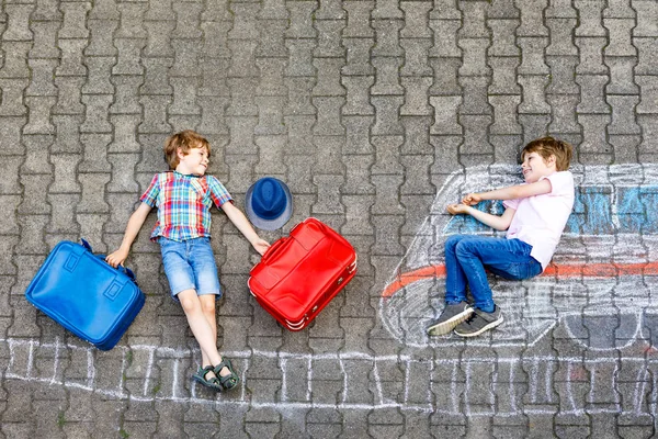 Два маленьких мальчика веселятся с рисунком поезда с красочными мелом на земле — стоковое фото