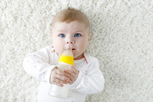 Cute adorable ewborn baby girl holding nursing bottle and drinking formula milk — Stock Photo, Image