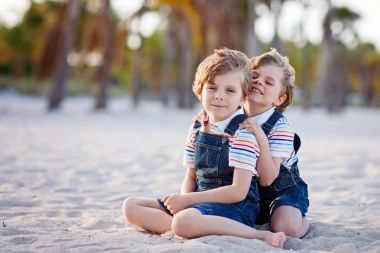 İki küçük çocuk tropik sahilde eğleniyor.