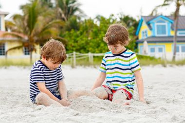 İki küçük çocuk tropik sahilde eğleniyor.