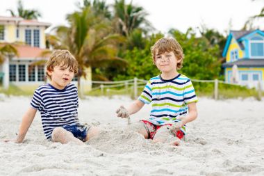 İki küçük çocuk tropik sahilde eğleniyor.