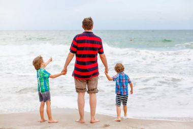 İki küçük çocuk çocuklar ve babası okyanus plaj