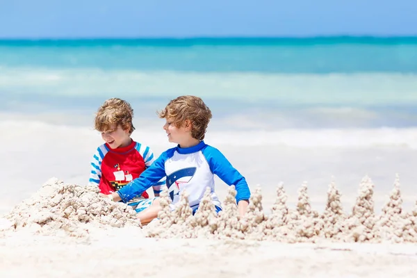 Due bambini ragazzi costruiscono castello di sabbia sulla spiaggia tropicale di Playa del Carmen, Messico — Foto Stock