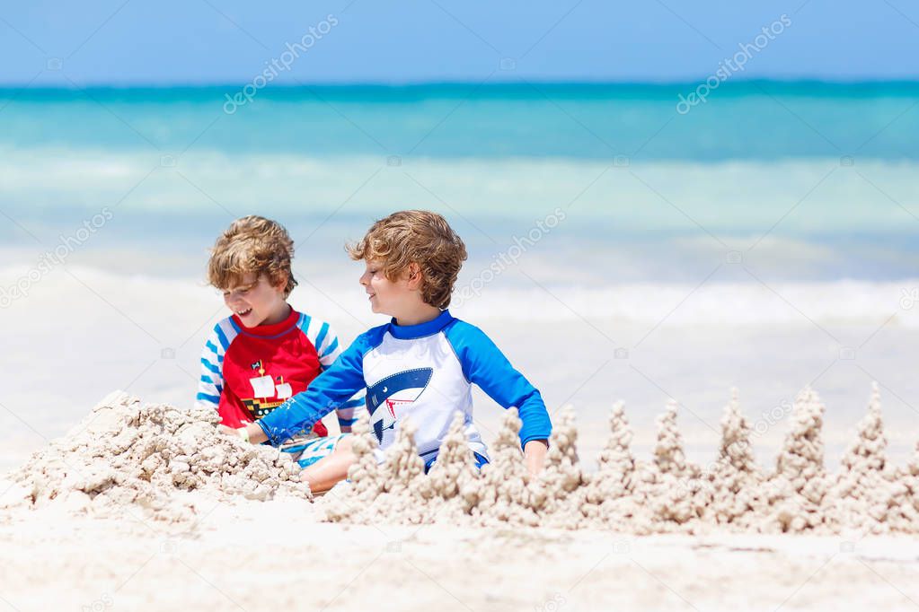 Two kid boys building sand castle on tropical beach of Playa del Carmen, Mexico