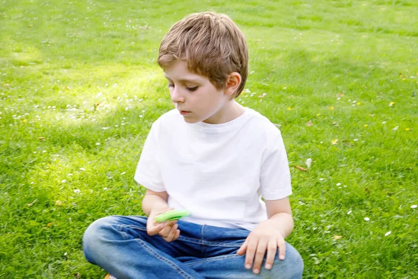 Ragazzo della scuola che gioca con Tri Fidget Hand Spinner all'aperto — Foto Stock