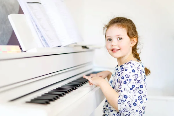 Beautiful little kid girl playing piano in living room or music school — Stock Photo, Image