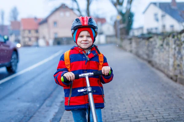 Cute little preschool kid boy riding on scooter riding to school. — Stock Photo, Image