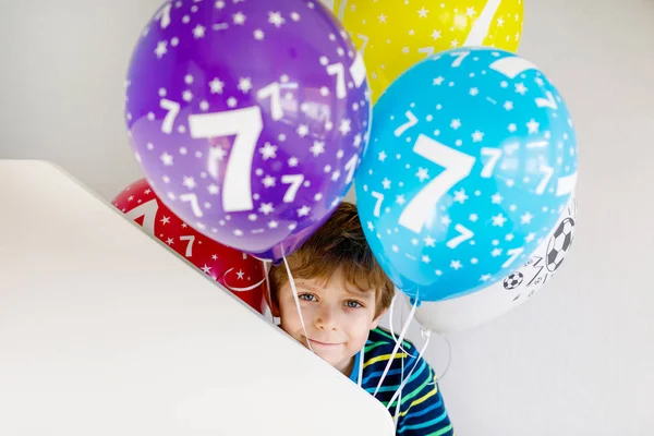 Portrait of happy kid boy with bunch on colorful air balloons on 7 birthday