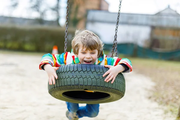 Grappig kind jongen hebben plezier met ketting swing op outdoor speeltuin — Stockfoto
