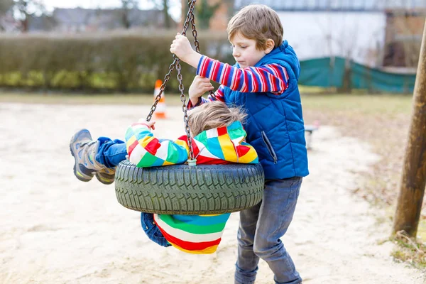 Dois garotinhos se divertindo com balanço de corrente no playground ao ar livre — Fotografia de Stock