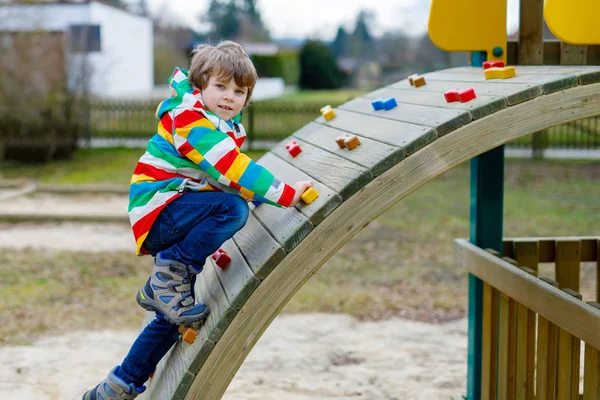 Niño rubio feliz divirtiéndose y escalando en el patio al aire libre — Foto de Stock