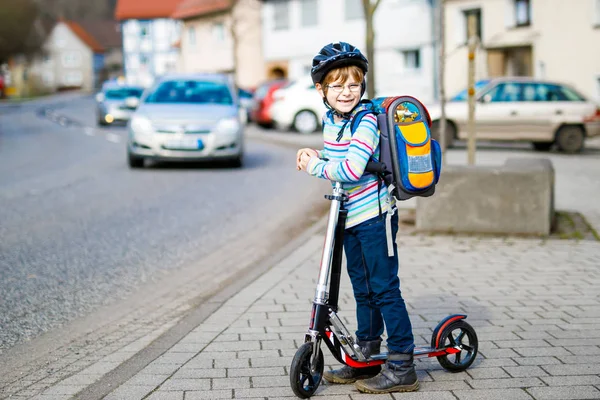 Niño en casco montado con su scooter en la ciudad — Foto de Stock