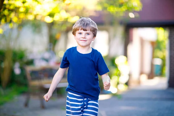 Pequeño chico rubio divertido jugando al hopscotch en el patio al aire libre —  Fotos de Stock