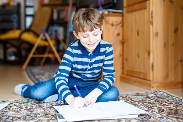 Niño preescolar en casa haciendo tarea, pintando una historia con plumas de colores — Foto de Stock