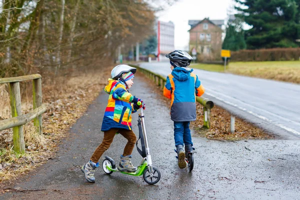 Dos niños pequeños, mejores amigos montando en scooter en el parque — Foto de Stock