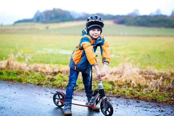Bonito menino pré-escolar montando em scooter no parque — Fotografia de Stock